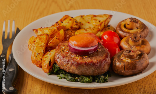 Beef burger dinner with potato wedges, tomatoes and mushrooms.