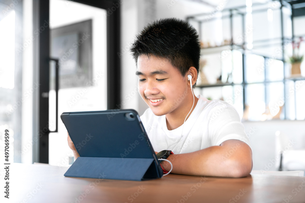 asian happy boy student wear headphone and study online with video call teached by teacher with smart tablet and laptop from home during covid-19 asian happy boy student wear headphone and study online with video call teached by teacher with smart tablet and laptop from home during covid-19