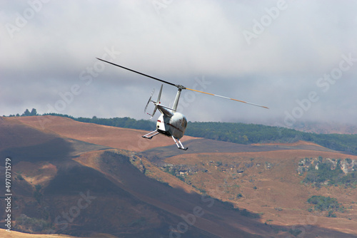White helicopter in flight over mountains