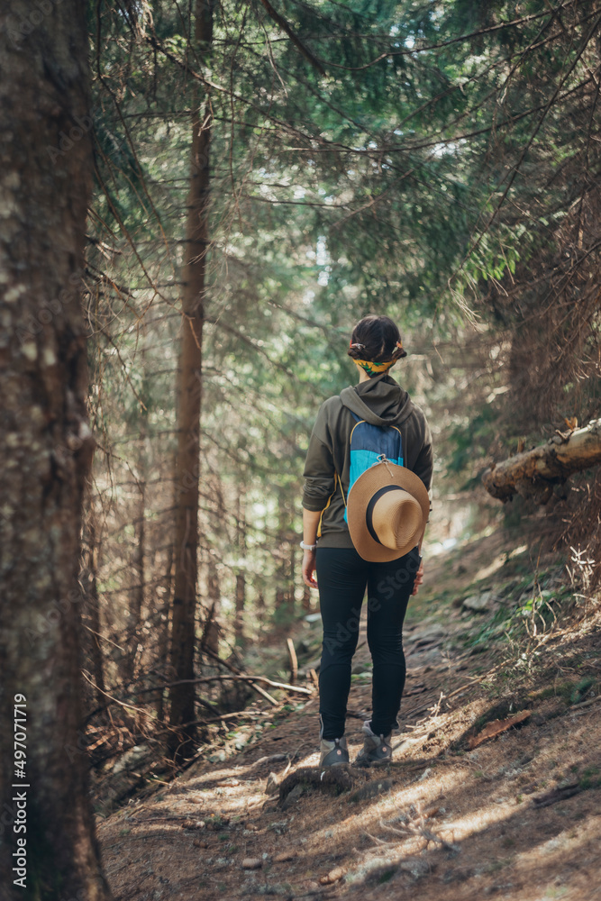 A girl in the forest with a hat on her back stands on the path A girl in the forest with a hat on her back stands on the path