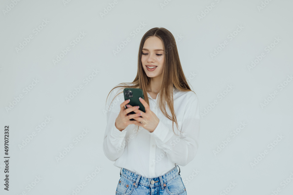 Portrait of smiling attractive woman texting on mobile phone while standing isolated over white background Portrait of smiling attractive woman texting on mobile phone while standing isolated over white background