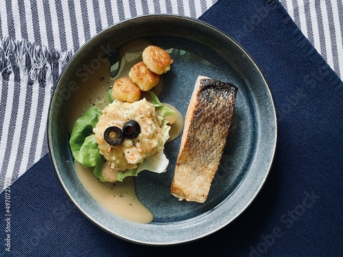 Flavorful Salmon, Scallop and Mashed Potato Platter, garnished with olives and lettuce, with a blue background to bring out the temperature of the food.