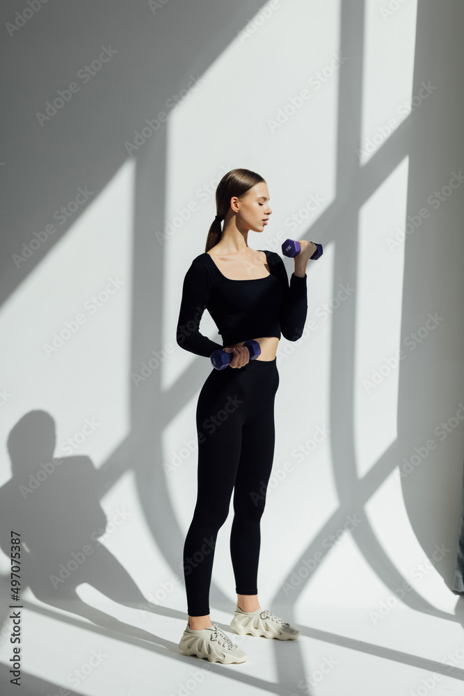 Obraz premium Fitness woman with dumbbell on white background.
