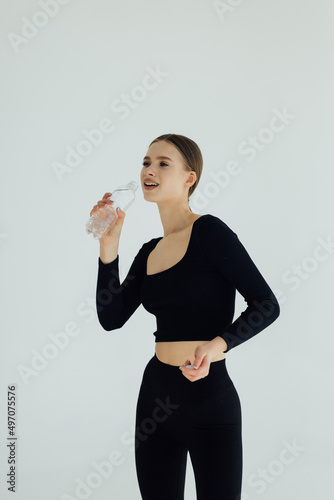 Woman in sportswear drinking water, isolated on white background