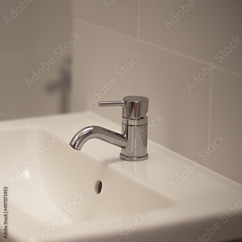 Water faucet with a bathtub on the background of a white sink  selective focus