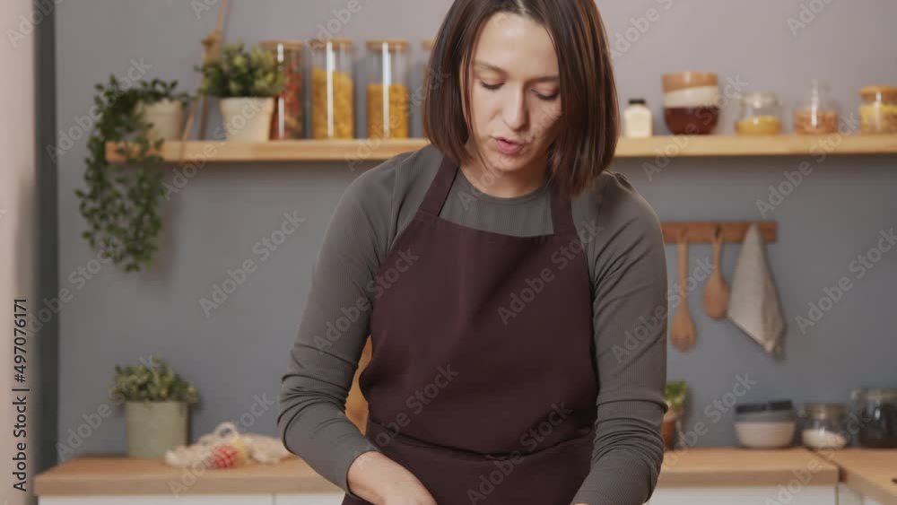 Tilt up shot of female culinary blogger cutting bell pepper and speaking on camera while filming food vlog in kitchen Tilt up shot of female culinary blogger cutting bell pepper and speaking on camera while filming food vlog in kitchen