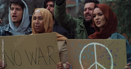 Group of young confident activists pacifists with placards with symbol of peace and phrase 