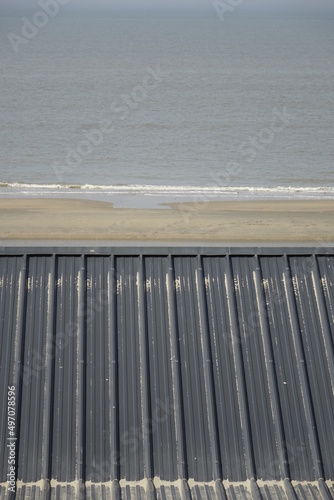 Top of black metal roof of beach hut over sandy North Sea beach, use: background, copy space (vertical), Zandvoort, North Holland, Netherlands