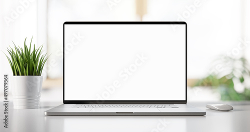 Laptop with blank screen on table in bright livingroom - home office background