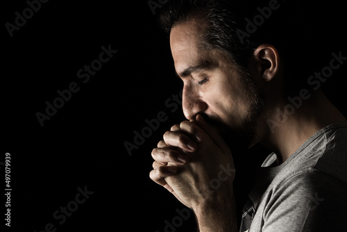 Fotografia The man folding his hands in prayer to god on a black background