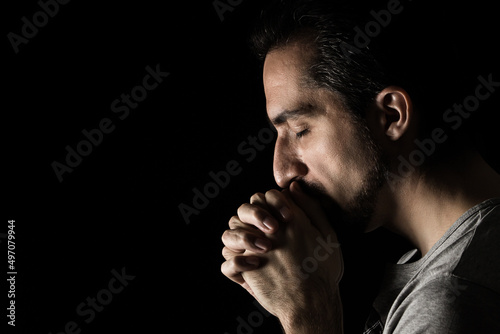 Fotografie The man folding his hands in prayer to god on a black background