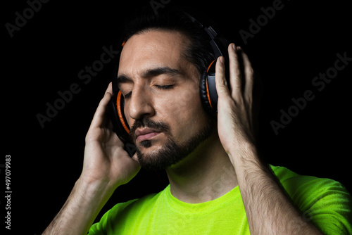 The guy listens to music in big headphones on a black background. Enjoy good music. Music therapy