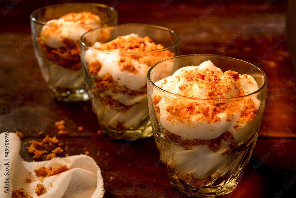 three glasses filled with yogurt and crumbled cookies three glasses filled with yogurt and crumbled cookies