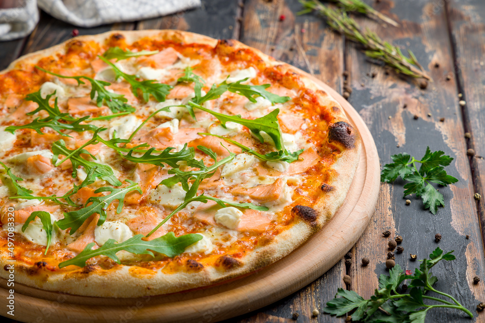 Pizza with salmon, Philadelphia cheese and aragula on old wooden table macro close up Pizza with salmon, Philadelphia cheese and aragula on old wooden table macro close up