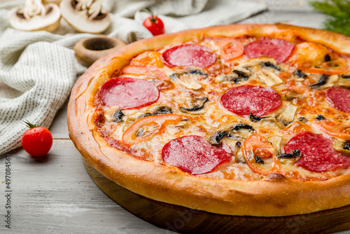 Pepperoni pizza with mushrooms and vegetables on grey wooden table macro close up