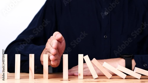 Businessman hand stopping continuous failing domino wooden effect. Concept of Risk Management, Business Crisis, Domino Effect, Investment, Finance, Risk, Disaster, Protection, Prevention, Opportunity