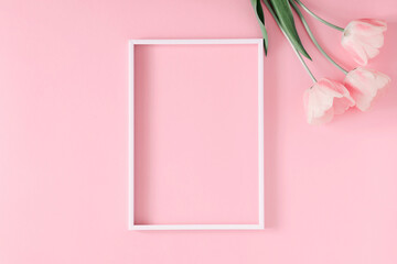 Beautiful composition, spring flowers. Blank frame for text, pink tulips flowers on pastel pink background. Valentine's Day, Easter, Birthday, Happy Women's Day. Flat lay, top view, copy space
