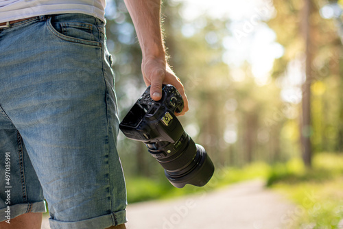 Close up of a man holding a professional camera at nature scenery