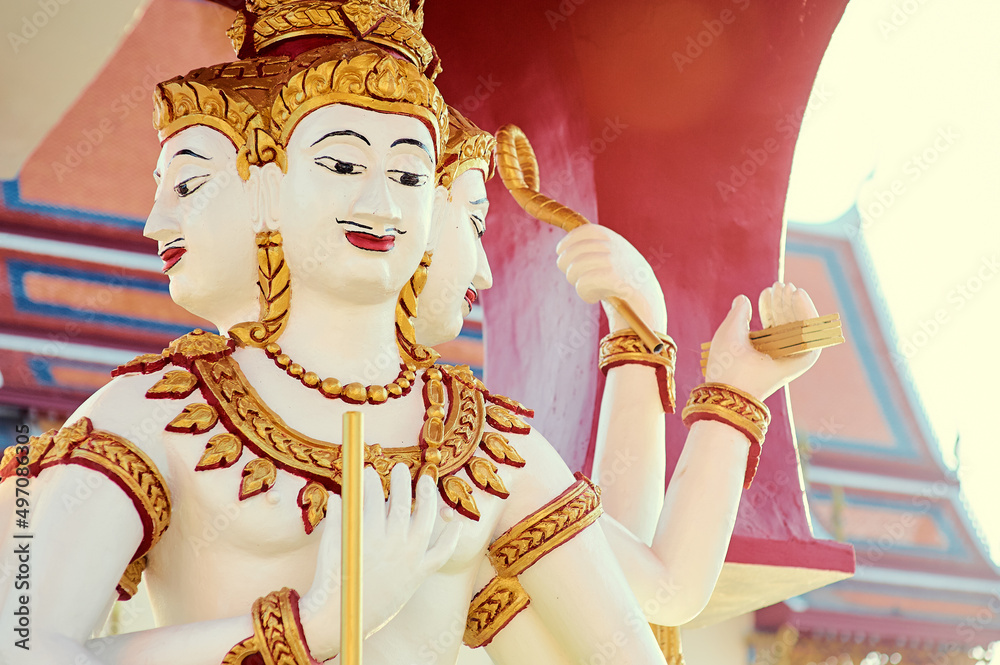 Fototapeta premium A cloesup view on a white-golden statue with three heads and six arms in Koh Samui Temple.