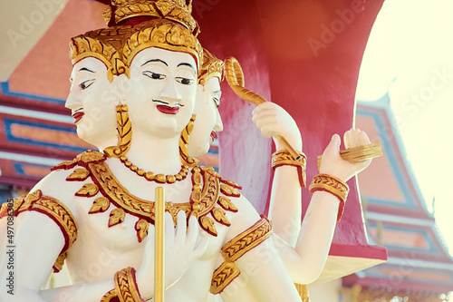 A cloesup view on a white-golden statue with three heads and six arms in Koh Samui Temple.