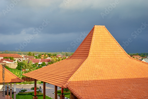 Balinese architecture  orange roof against a resort settlement during a stormy weather.  Bali  Indonesia.