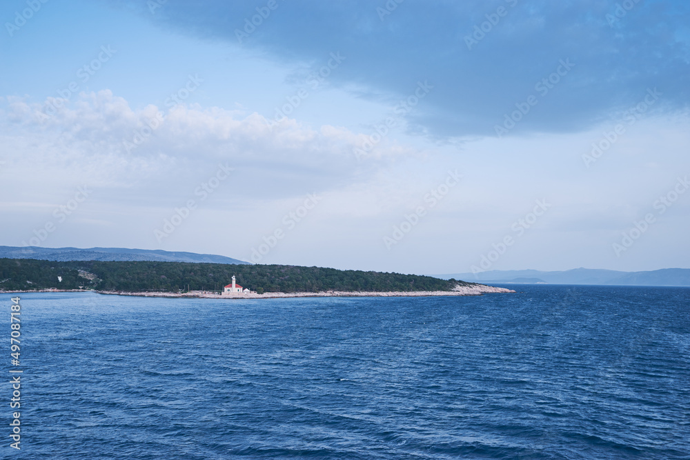 Seascape with blue sea and sky. Lighthouse on a coast.
