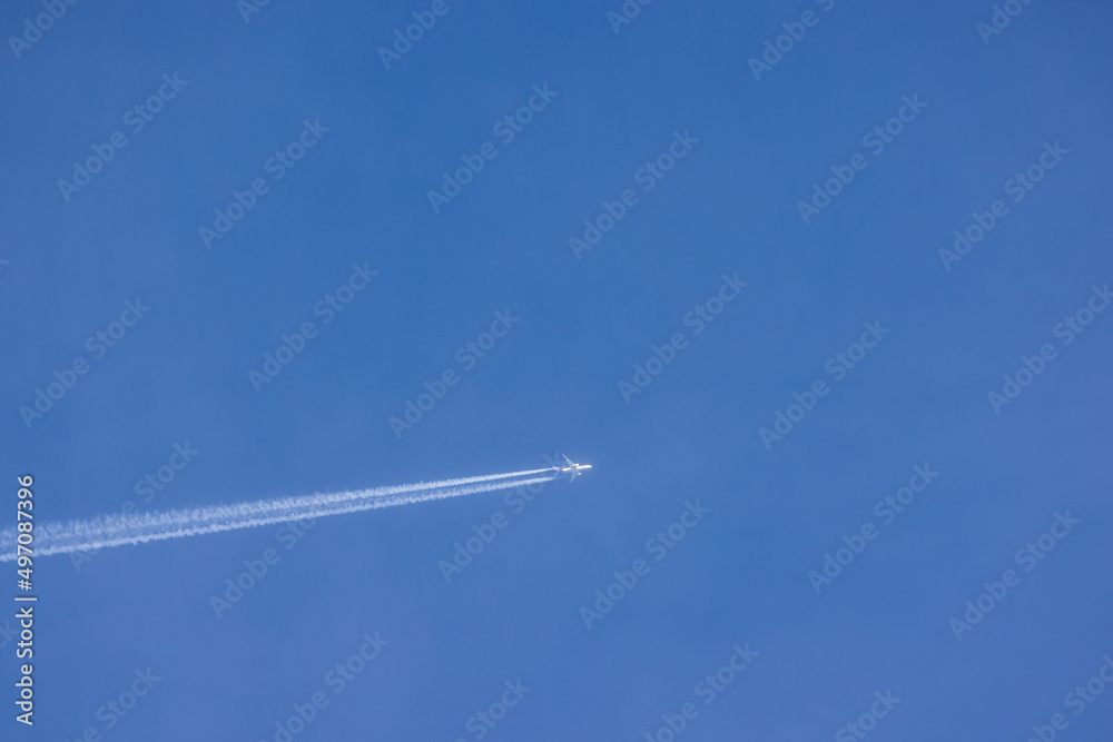 Passenger airplane and contrails against clear blue sky Passenger airplane and contrails against clear blue sky