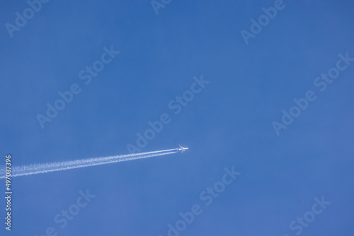 Passenger airplane and contrails against clear blue sky