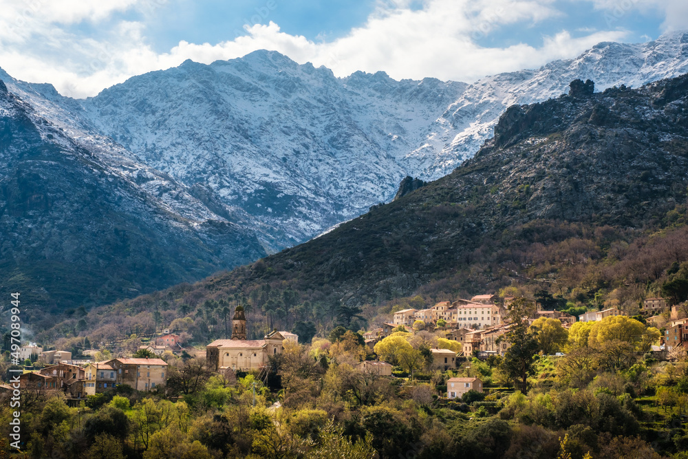 The village of Feliceto in the Balagne region of Corsica with snow capped mountains in the distance