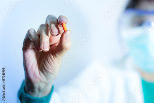 Pill close-up. Doctor's hand holding antiviral pill. Medicine. Orange pill. Treatment against disease. Health and disease concept. Covid 19 treatment