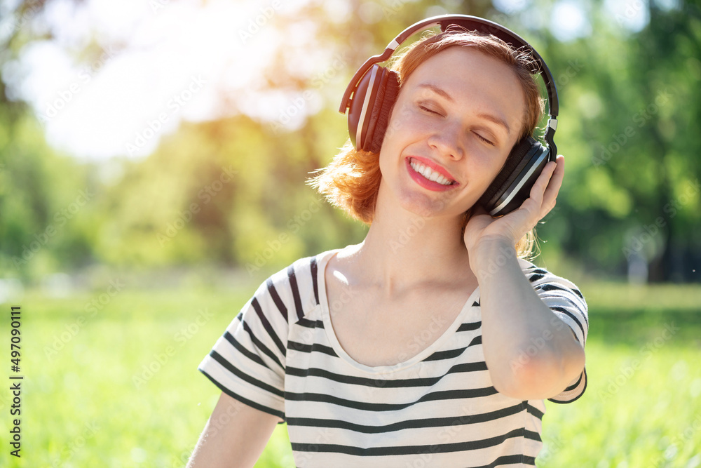 Young woman happens to have music in a summer park Young woman happens to have music in a summer park