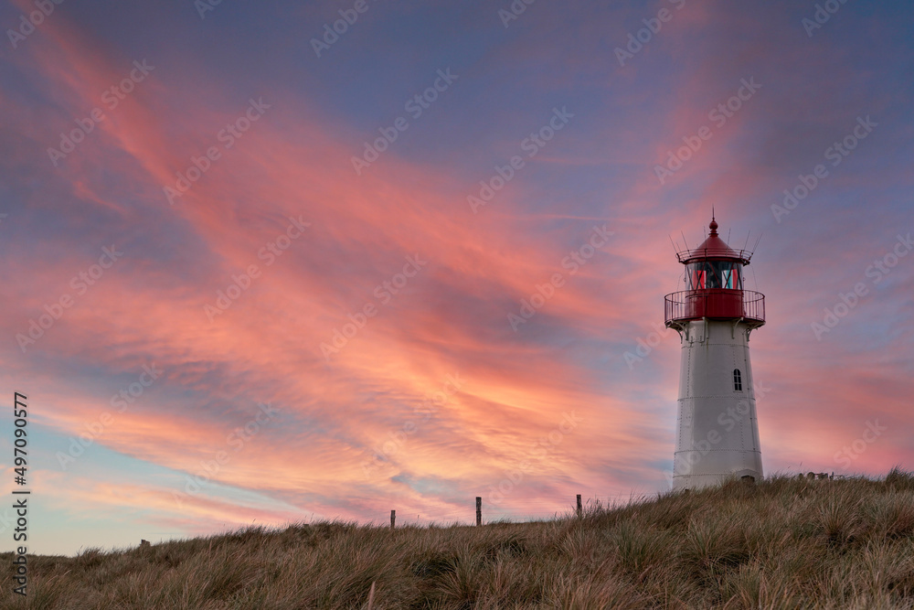 Lighthouse List-West on the island Sylt at sunset. Dramatic sunset sky and lighthouse.