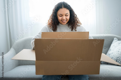 Excited young woman unpacking huge carton box sit on sofa at home