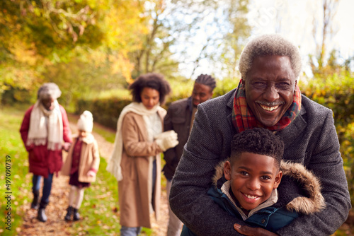 Smiling Multi-Generation Family Having Fun Walking Through Autumn Countryside Together