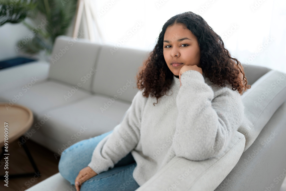 Pensive young African woman sitting on the couch at home Pensive young African woman sitting on the couch at home
