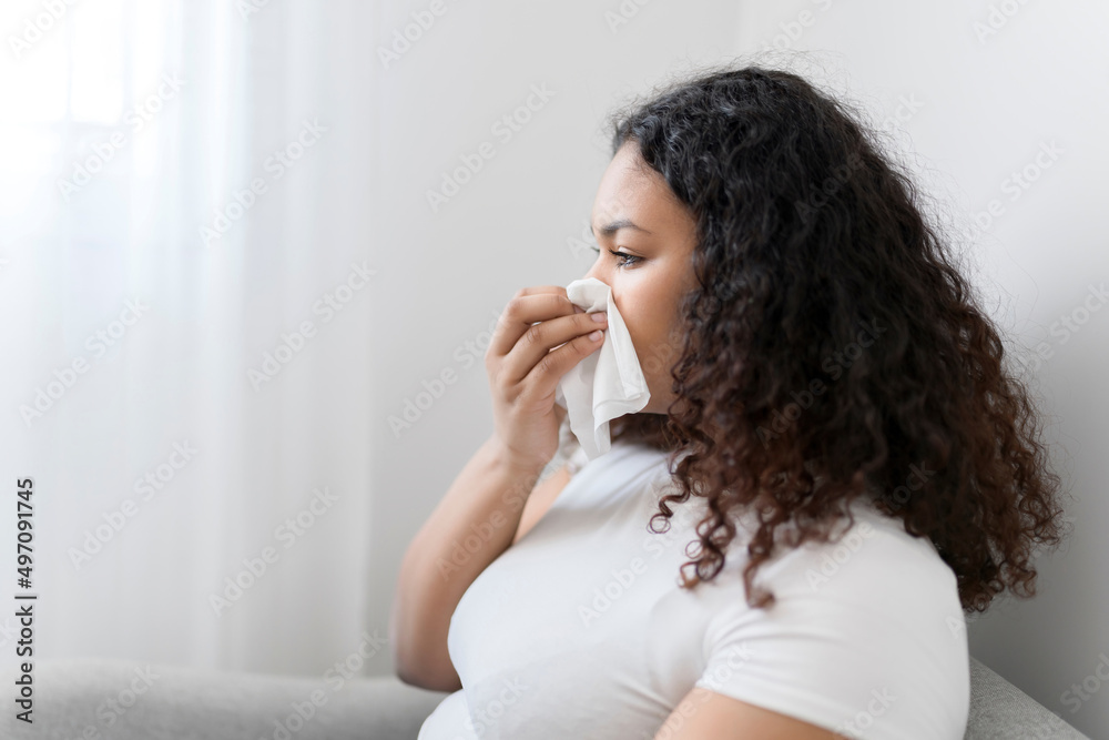Sick ill black woman with tissue sitting on sofa Sick ill black woman with tissue sitting on sofa