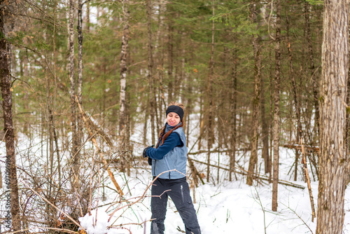 A young woman on snowshoes plays with snowballs in the boreal forest. Shot in the Ottawa Valley, Ontario Canada.