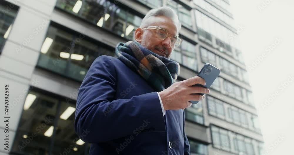 A man uses a mobile phone, standing in business center of the city A man uses a mobile phone, standing in business center of the city