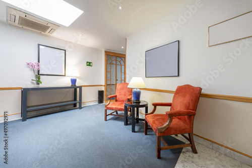 Wooden armchairs upholstered in orange velvet on a blue carpet in a hall