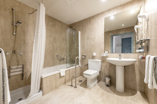 bathroom with shower cabin  separate tub  frameless mirror  marble walls and floor and accessories for the disabled