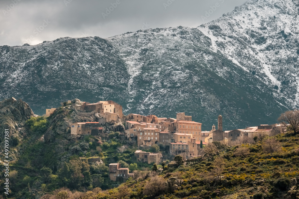 The village of Speloncato in the Balagne region of Corsica with snow capped mountains behind