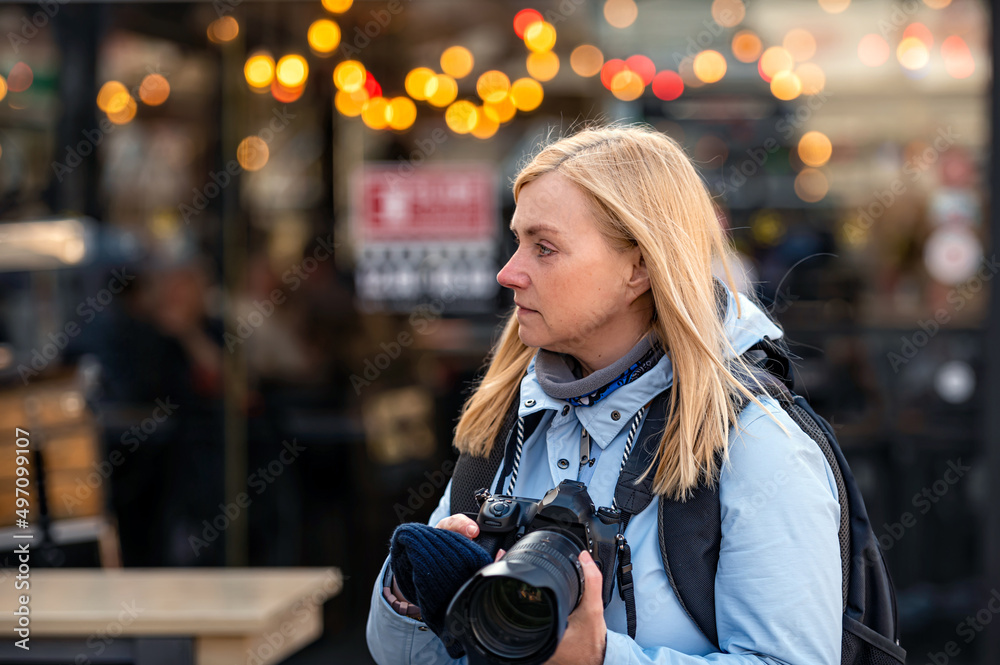 blonde middle-aged female with a camera in the evening on the city streets, lifestyle concept blonde middle-aged female with a camera in the evening on the city streets, lifestyle concept