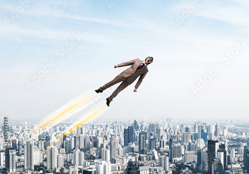 Businessman in suit and aviator hat flying in sky