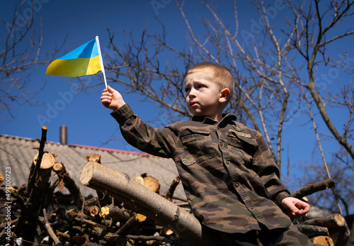 The child holds in his hands a small flag of Ukraine in the hope of peace. Save Ukraine
