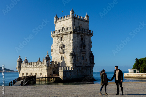 Woman and man next to the Belem Tower in Lisbon, Portugal.