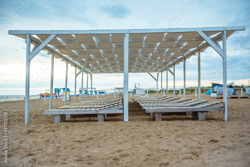 Sandy beach with sun loungers and a wooden canopy in a tropical resort on the Red Sea coast in Sharm El Sheikh, Egypt, Africa. Empty beaches during quarantine and war
