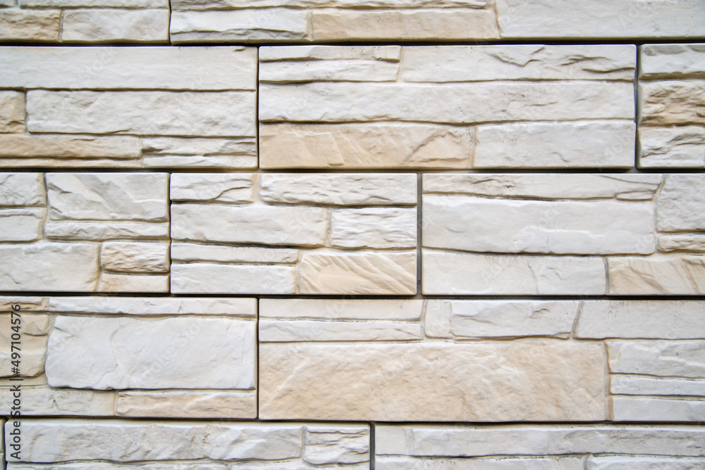 Naklejka premium Background of beige bricks. Wall of beige bricks. The texture of the wall. Texture of beige decorative tiles in form of brick.