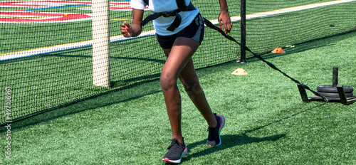 Runner pulling a sled with weights on a green turf field photo