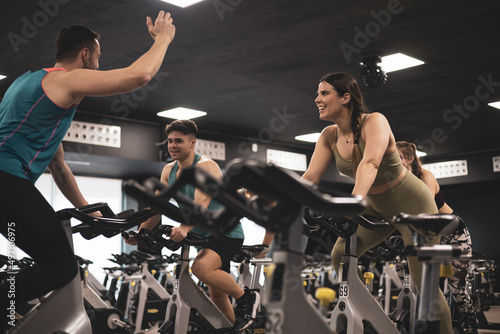 people on bikes in spinning class in modern gym, exercising on stationary bike. group of athletes training on exercise bike photo