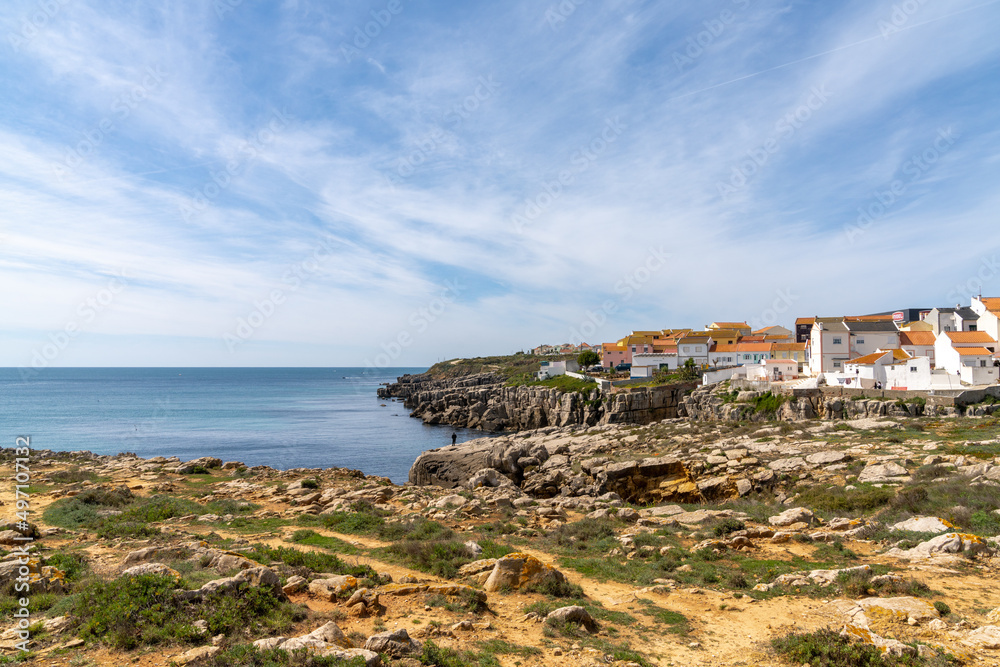 view of the jagged rocky coast and colorful houses in the center of Peniche
